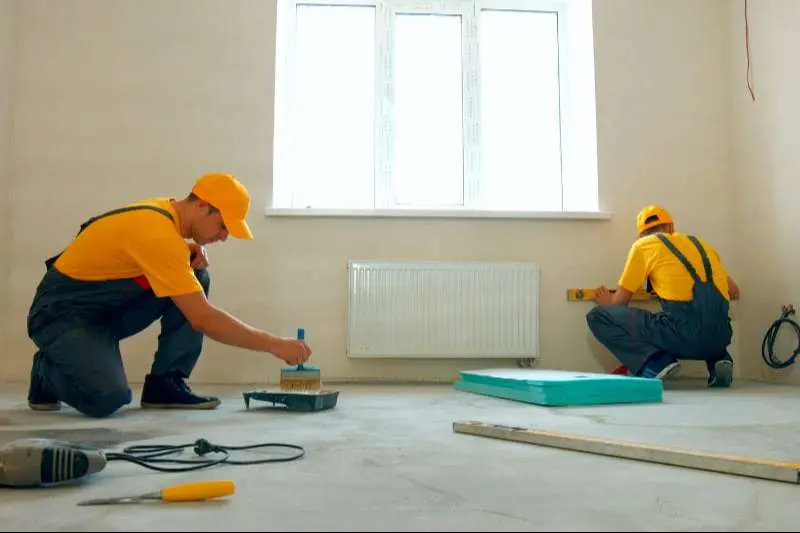 ремонт на апартамент работници с жълти шапки тениски и сиви гащеризони извършват ремонт на апартамент